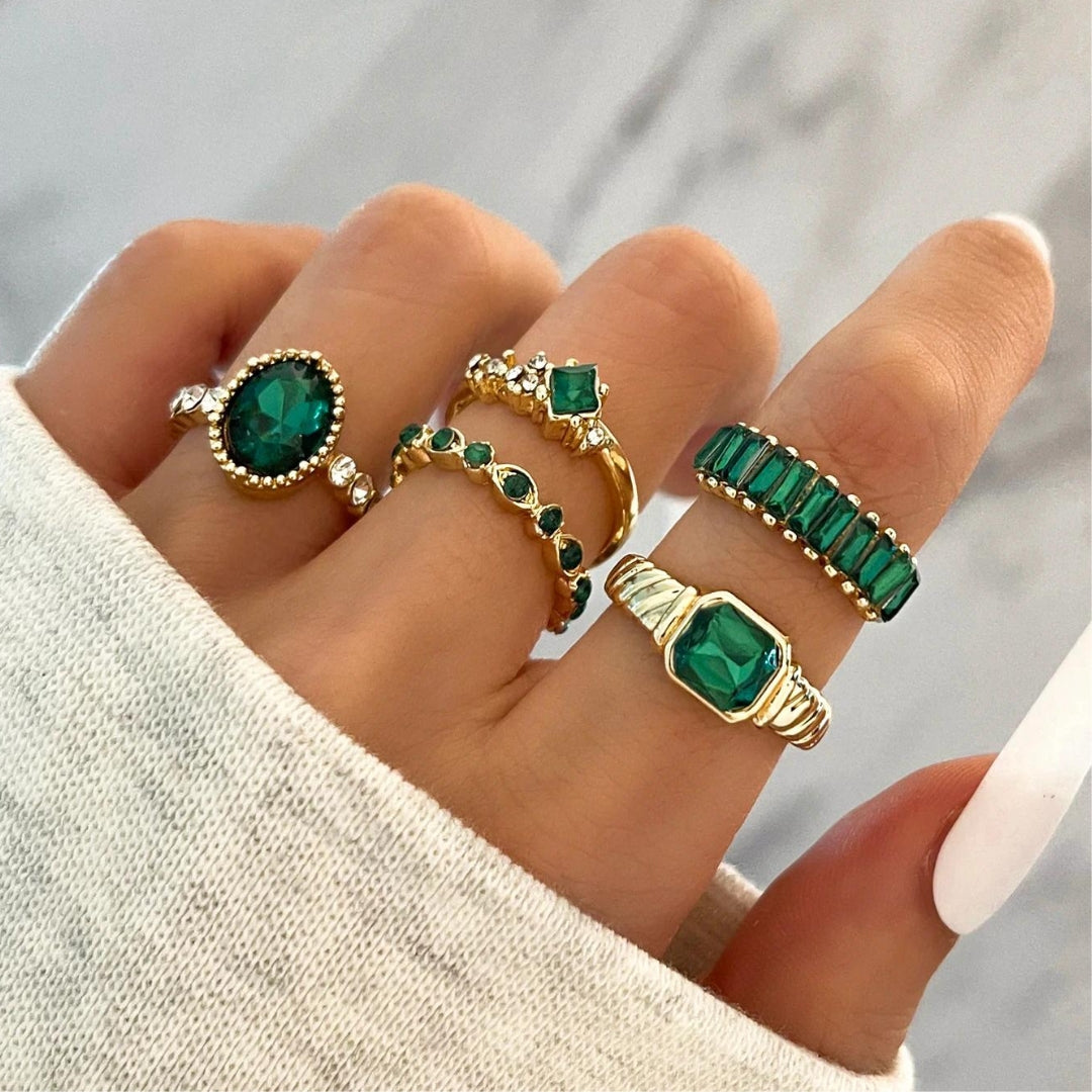 Anéis dourados brilhantes com pedras de zircônia verde radiante