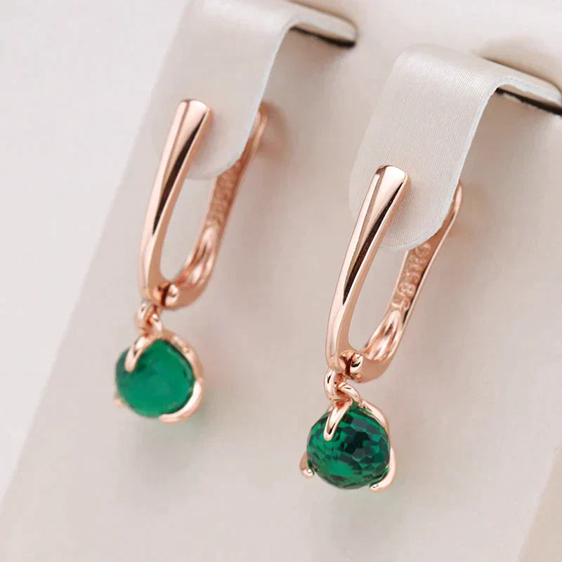 Elegantes brincos dourados adornados com brilhantes cristais verdes