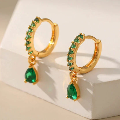 Brilhantes brincos dourados com zircônias cintilantes e uma encantadora esmeralda verde