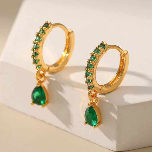 Brilhantes brincos dourados com zircônias cintilantes e uma encantadora esmeralda verde