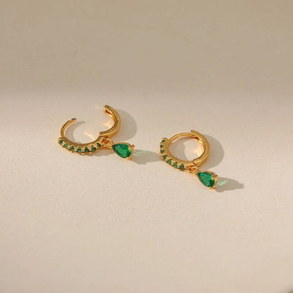 Brilhantes brincos dourados com zircônias cintilantes e uma encantadora esmeralda verde