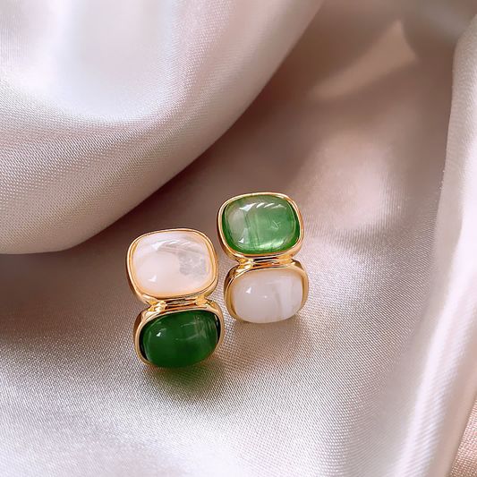 Elegantes brincos dourados com pedras preciosas brancas e verdes elaboradas